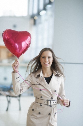 Businesswoman holding heart shaped balloon and smiling