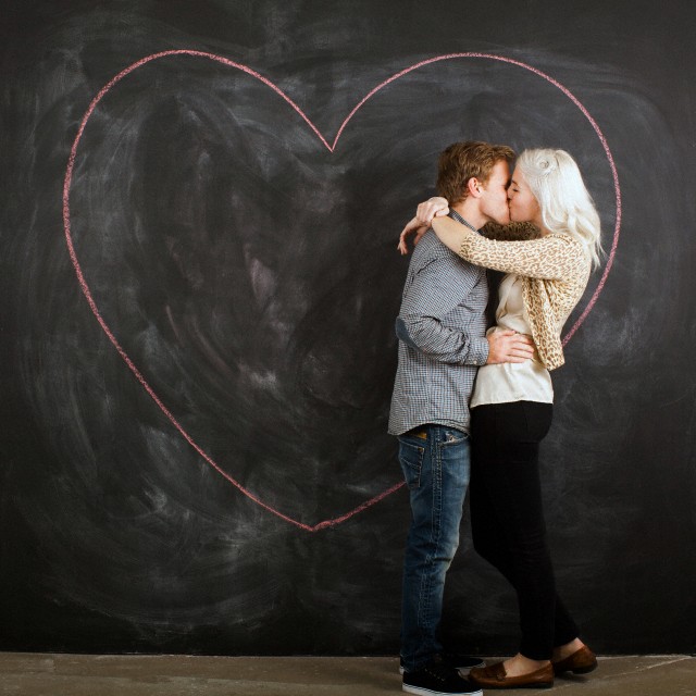 Studio portrait of young couple embracing in front of blackboard